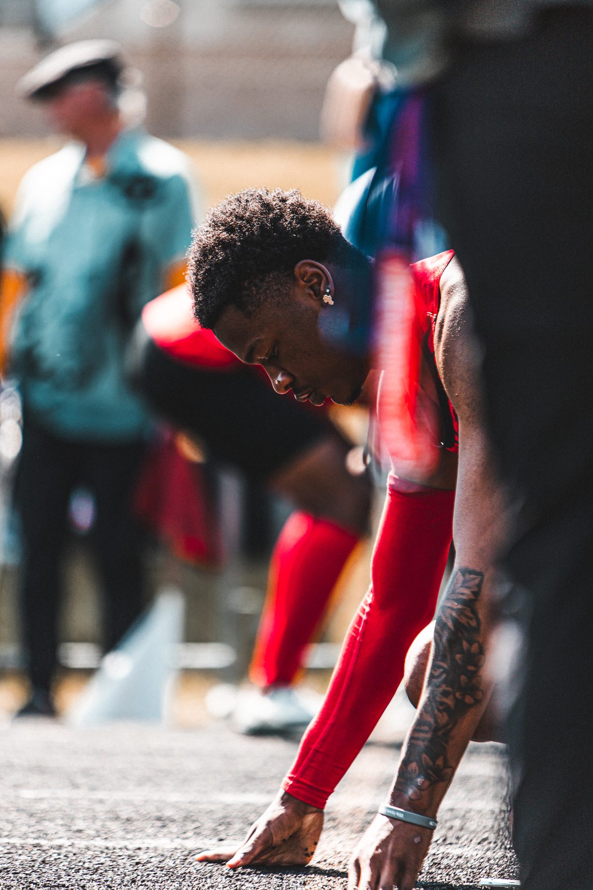 Sprinter in a red uniform setting his hands on the starting line before a race